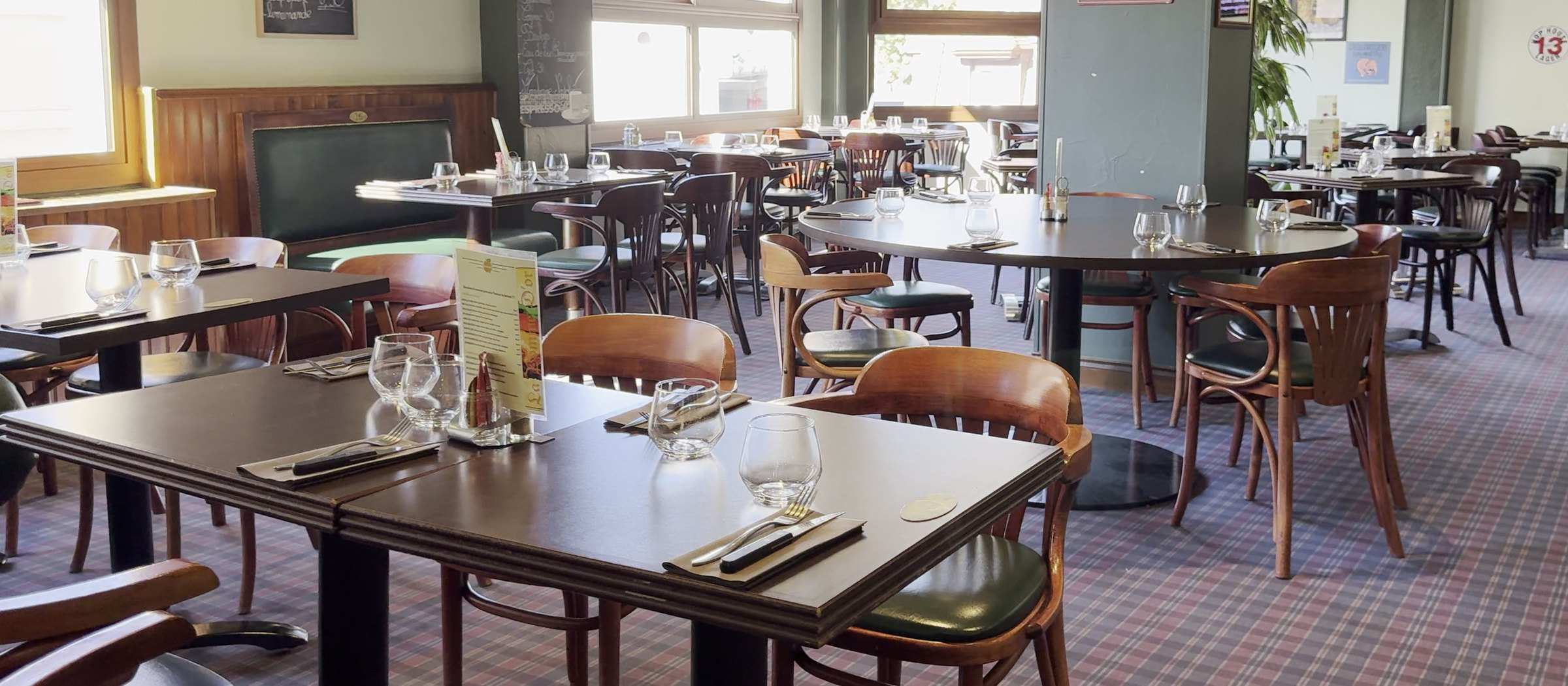 La grande salle de La Pomme d’Or, tables dressées sous les baies vitrées